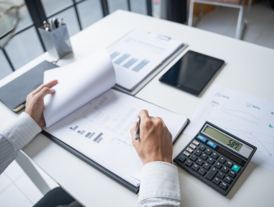 foto persona realizando una auditoria de cuenta, escritorio con informes y calculadora